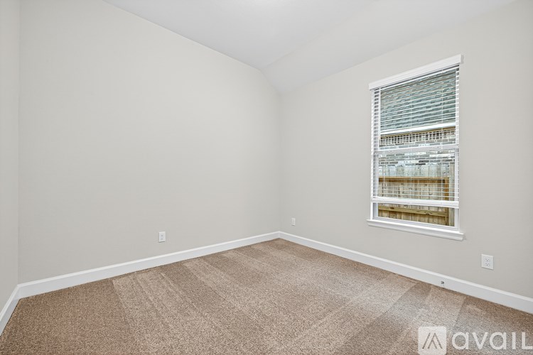 A room with a carpeted floor and a window with blinds.