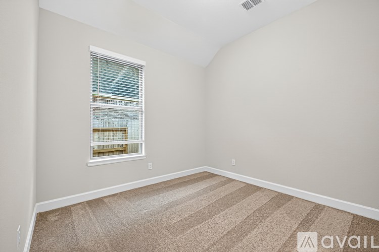 A room with a carpeted floor and a window with blinds.