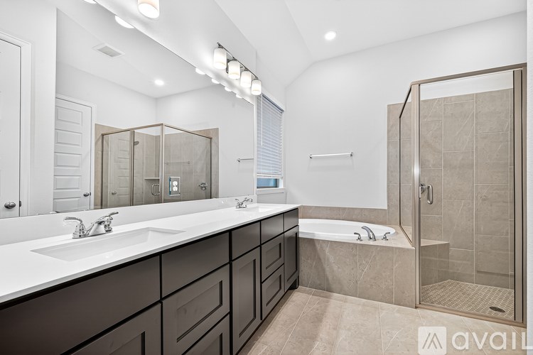 A modern bathroom with a large mirror, double sinks, and a walk-in shower.