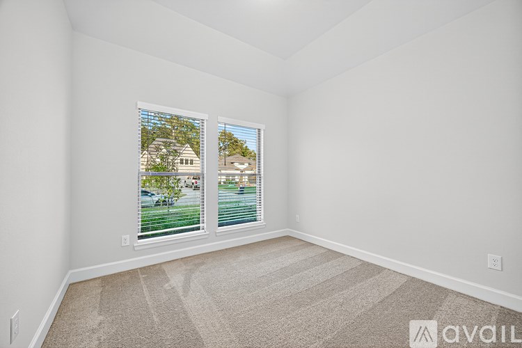 A room with a carpet floor and two windows showing an outdoor view.