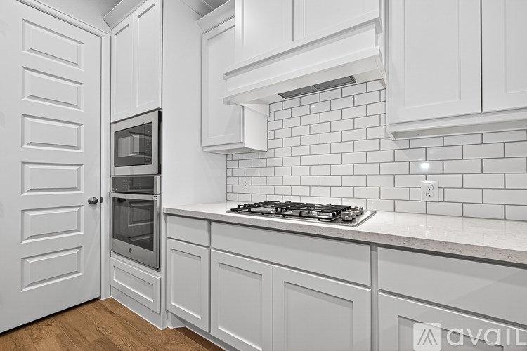 A kitchen with white cabinets and a white tiled backsplash.