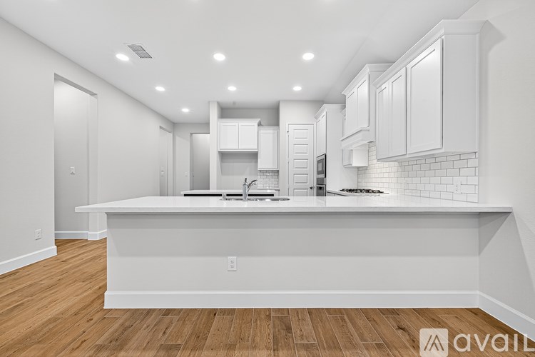 A modern kitchen with white cabinets and a wooden floor.