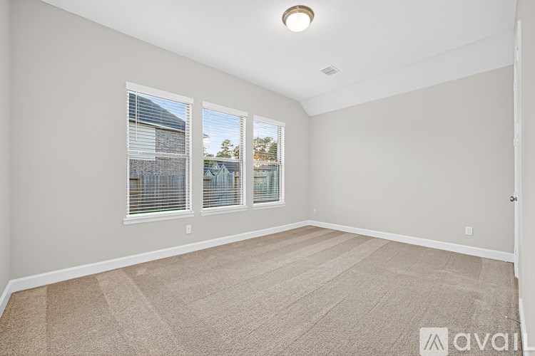 A room with beige carpeting and three windows.