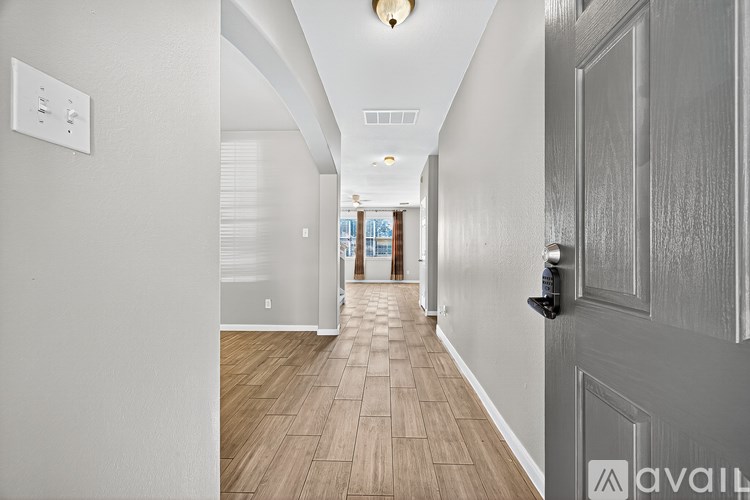 A long hallway with a door on the right and a light switch on the wall.
