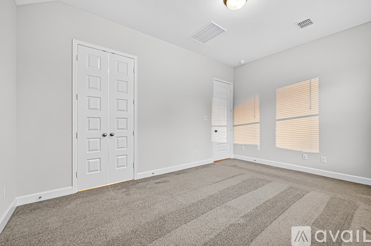 A room with a carpeted floor, a white door, and a window with blinds.
