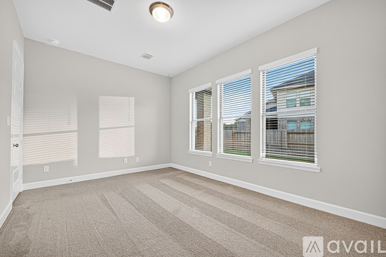 A room with a carpeted floor and a window with blinds.