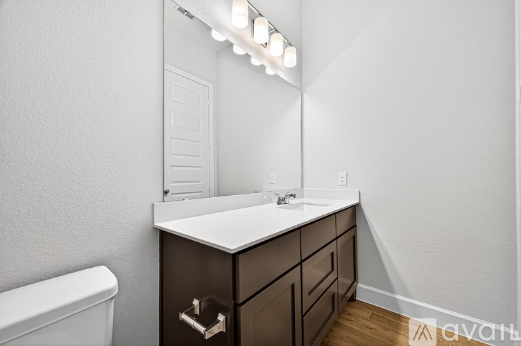 A bathroom with a white sink and brown drawers.