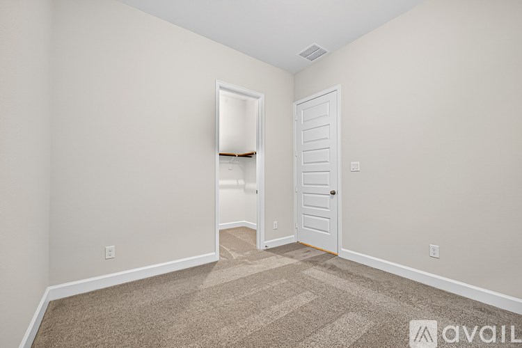 A room with a carpeted floor and two doors, one of which is open.