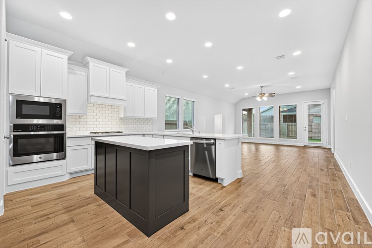 A spacious kitchen with wooden floors and white cabinetry.