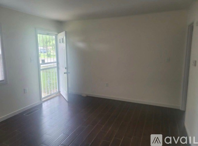 A room with wooden floors and a sliding glass door leading to a balcony.