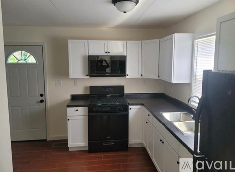 A kitchen with black appliances and white cabinets.