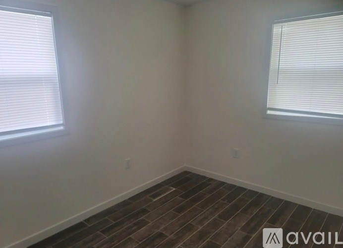 A room with a wooden floor and two windows.
