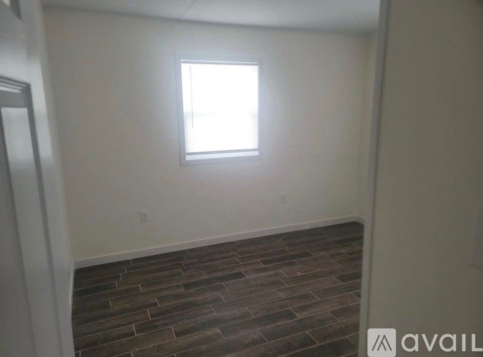 A room with a window and a wooden floor.