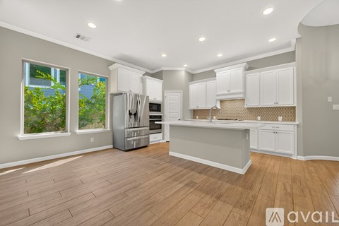 A kitchen with white cabinets and a wooden floor.