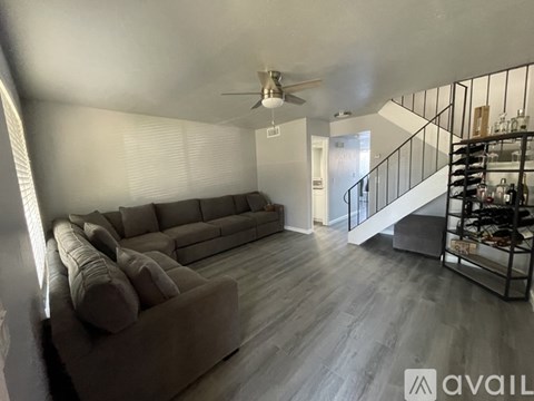 A living room with a grey couch and a fan.