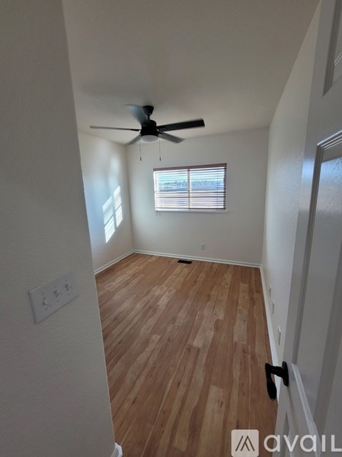 A room with a ceiling fan and wooden flooring.