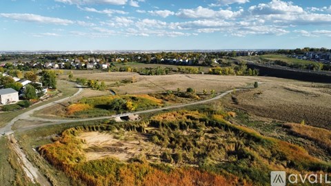 A large open field with a road running through it and a small white building to the left.