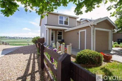 A house with a brown fence and a gravel driveway.