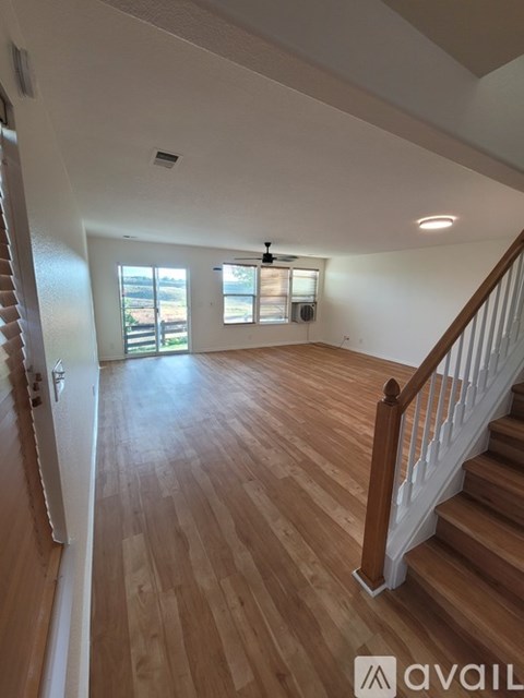 A room with wooden floors and a staircase leading to another room.