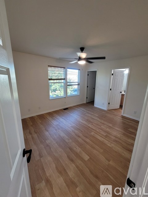 A room with wooden flooring and a ceiling fan.