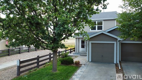 A house with a garage and a tree in front of it.