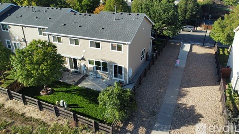 A house with a gravel driveway and a small tree in front.