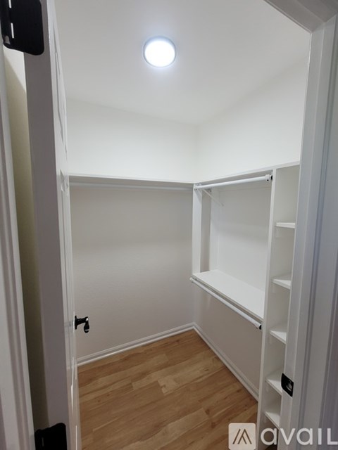 A small, empty room with a wooden floor and white walls.