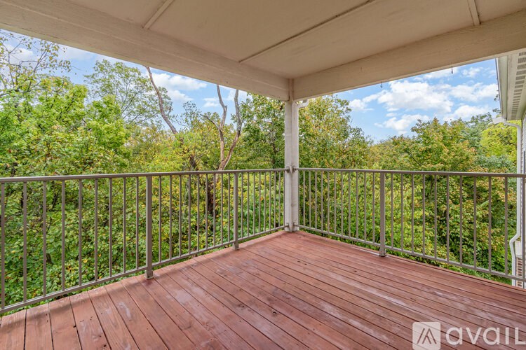 A wooden deck with a metal railing and trees in the background.