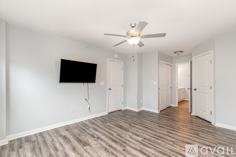 A spacious room with a ceiling fan and a flat screen TV mounted on the wall.