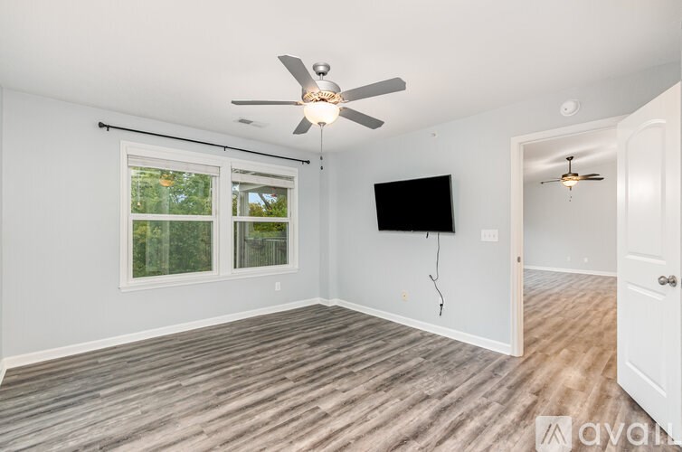 A room with a ceiling fan and a flat screen TV mounted on the wall.