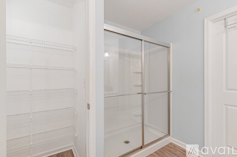 A walk-in closet with white shelves and a glass door.
