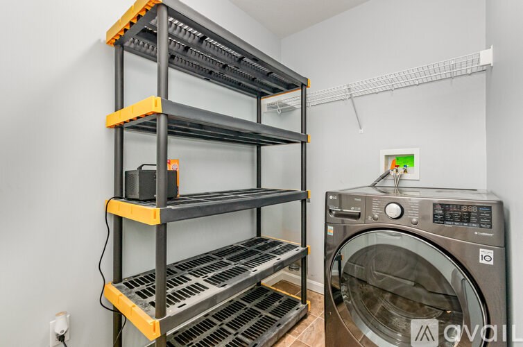 A laundry room with a washing machine and a shelving unit.