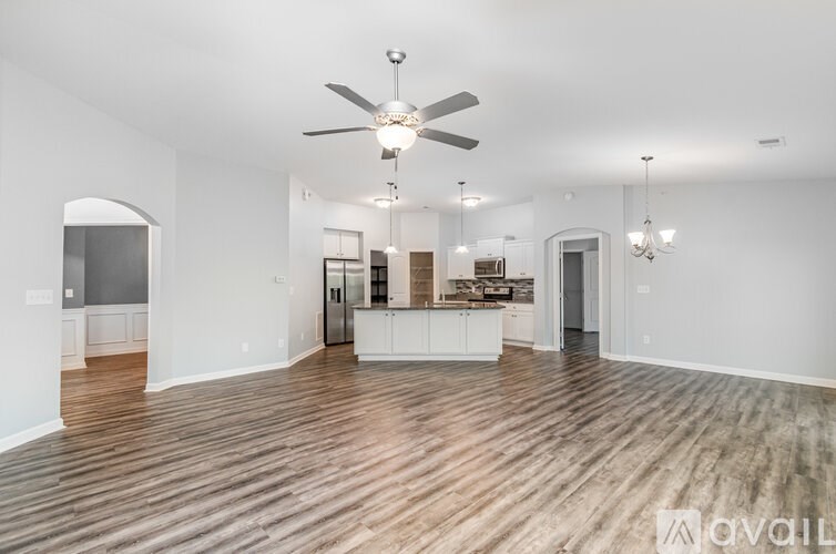 A spacious living room with a ceiling fan and hardwood floors.