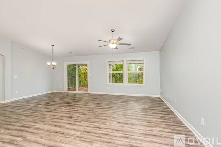 A spacious room with a ceiling fan and wooden flooring.