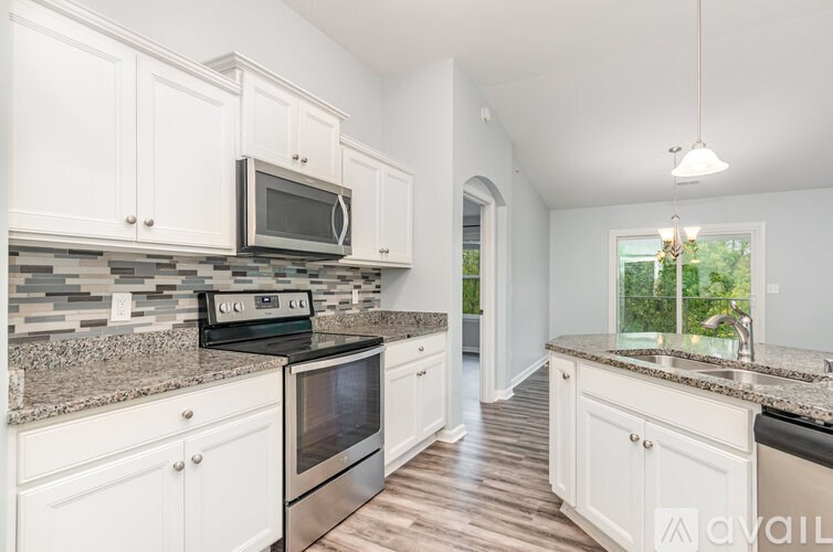A kitchen with white cabinets and a granite countertop.