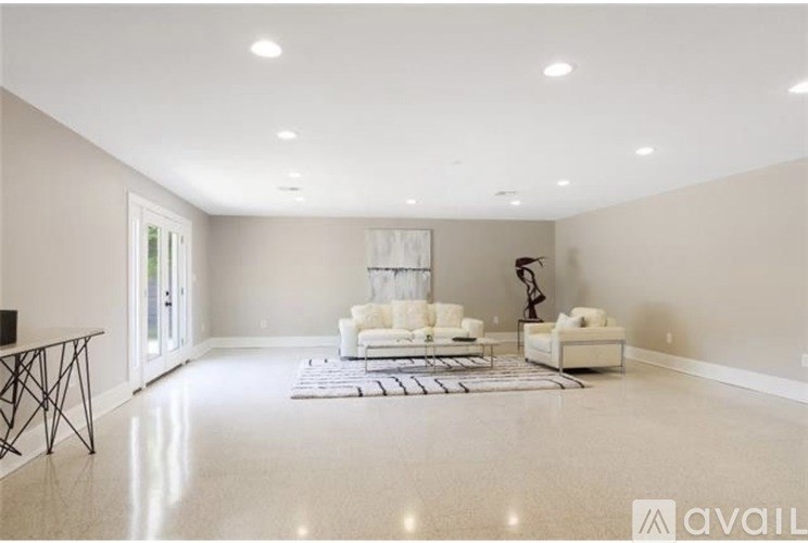 A spacious living room with a white sofa set and a black floor lamp.
