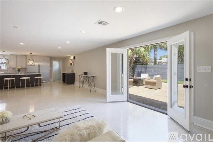A spacious living room with a white rug and a white couch.