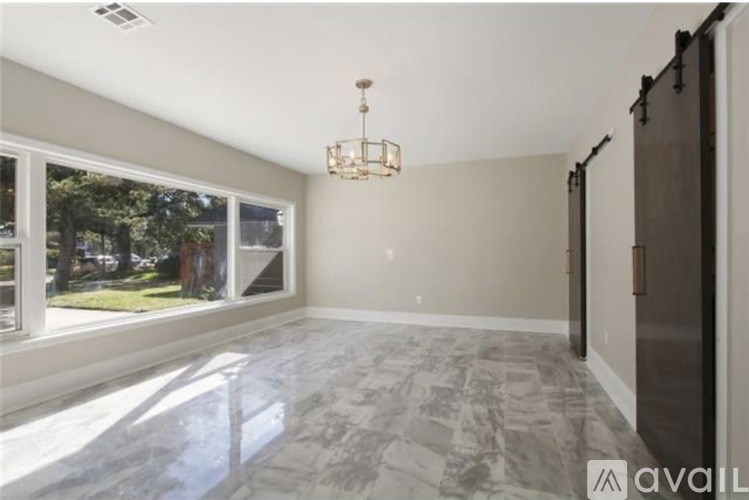 A spacious room with a marble floor and a chandelier hanging from the ceiling.