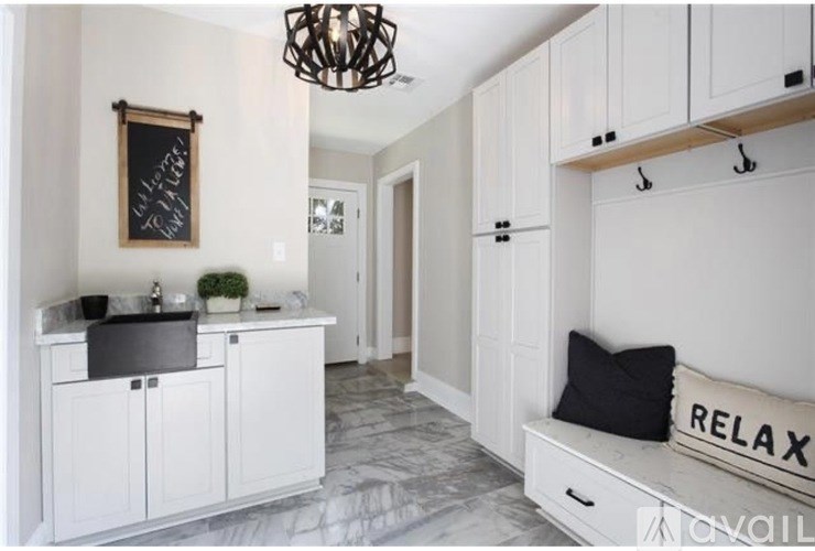 A kitchen with white cabinets and a black chalkboard on the wall.