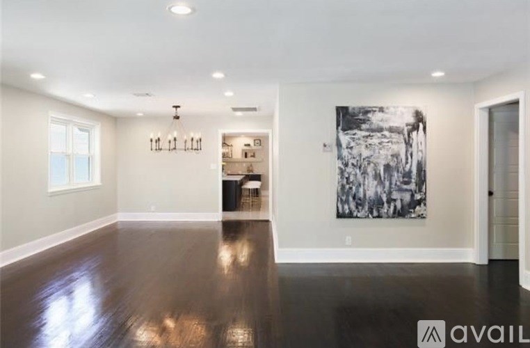 A spacious room with a large painting on the wall and a dark hardwood floor.
