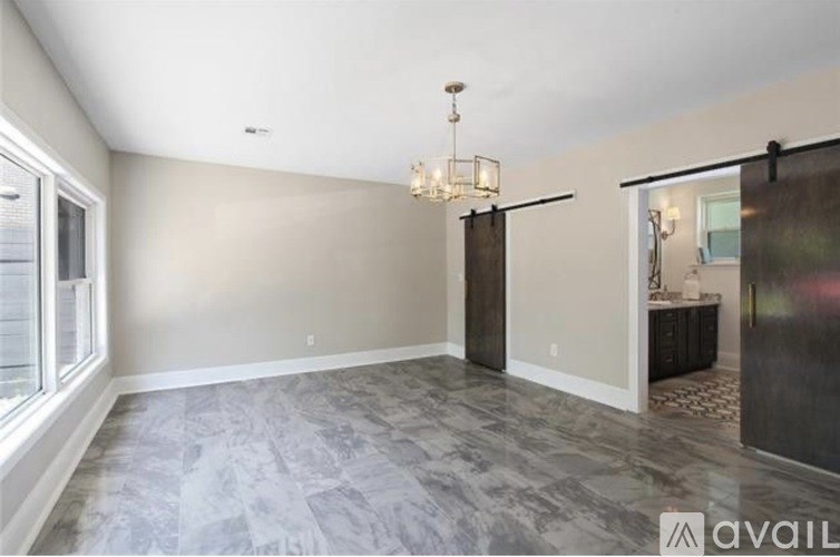 A spacious room with a grey marble floor and a chandelier hanging from the ceiling.