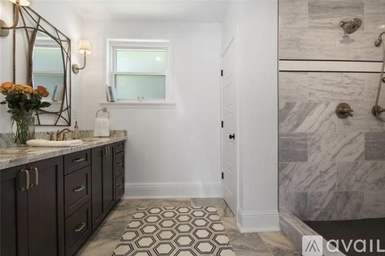 A bathroom with a marble tile floor and a mirror above a vanity.
