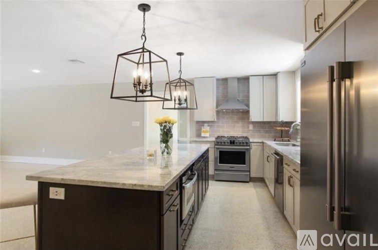 A modern kitchen with a marble countertop and stainless steel appliances.