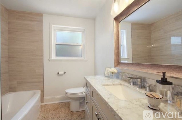A bathroom with a tub, toilet, sink and mirror.
