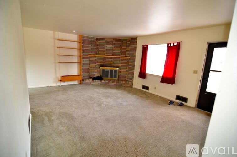 A room with a fireplace and a window with red curtains.