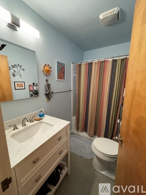 A bathroom with a sink, toilet, and striped shower curtain.