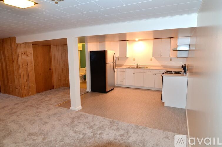 A kitchen with white cabinets and a black fridge is shown.