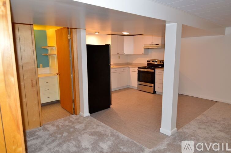 A kitchen with a black refrigerator and white cabinets.