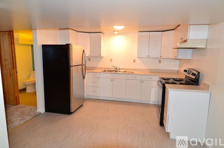 A kitchen with white cabinets and a black fridge.