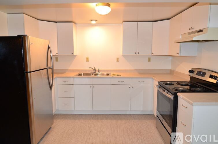 A kitchen with white cabinets and a black refrigerator.